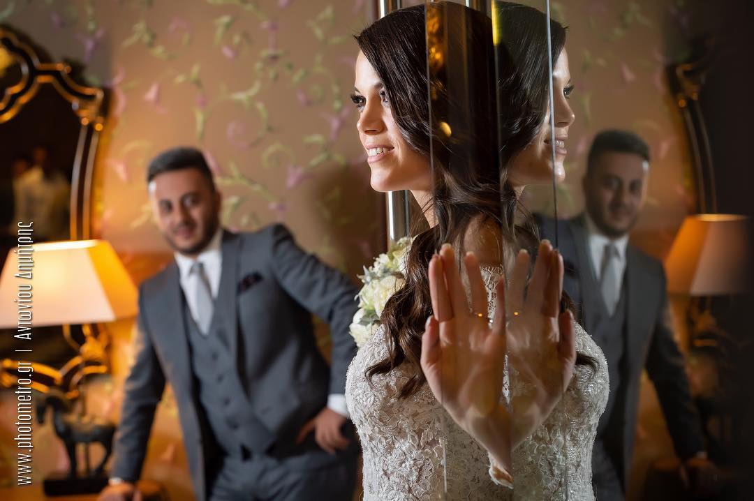 Bride's reflection with groom in the background